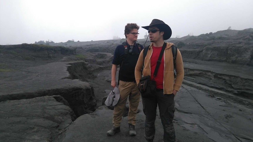 Two men standing on a mud plain in Indonesia.