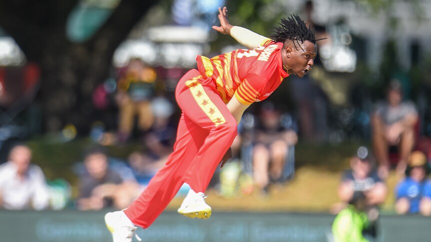 A Zimbabwe male ODI player bowls a ball against Australia.