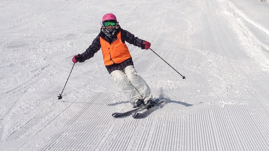 Vision impaired skier Debbie King skiing down the slopes of Mt Buller, wearing high vis