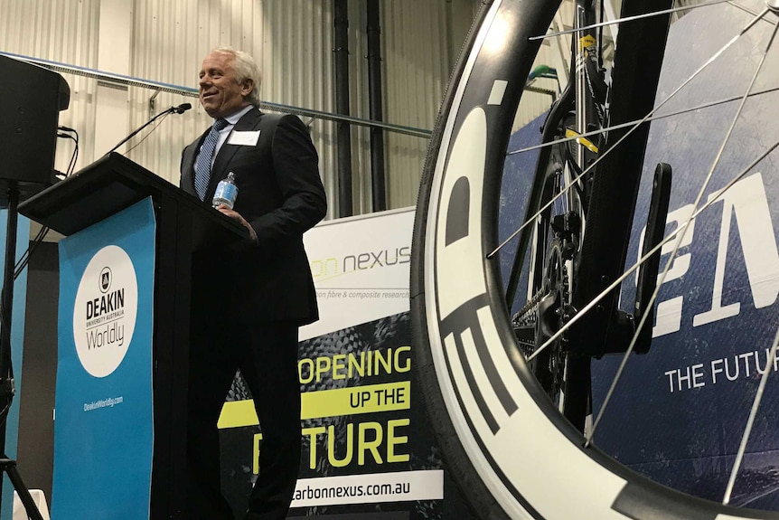 Tour de France winner Greg LeMond makes a speech at a lectern.