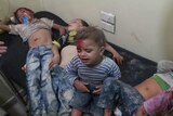 Injured children sit on a bed in the wake of a strike on Aleppo