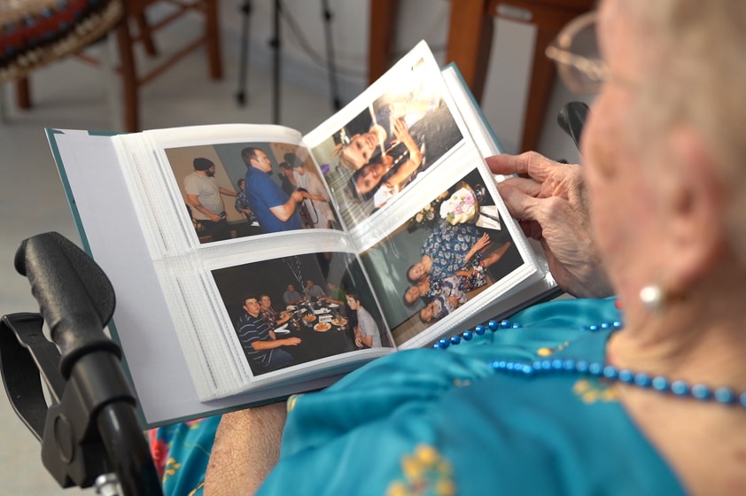 Aged care resident Enid Mallon holding a family picture album