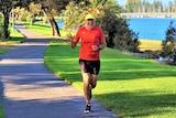 Steve Connelly is pictured waving to the camera as he runs along the Patawalonga river