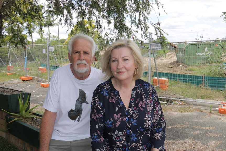 Unit owners Anthony and Julia Mayfield sit in front of construction fencing.