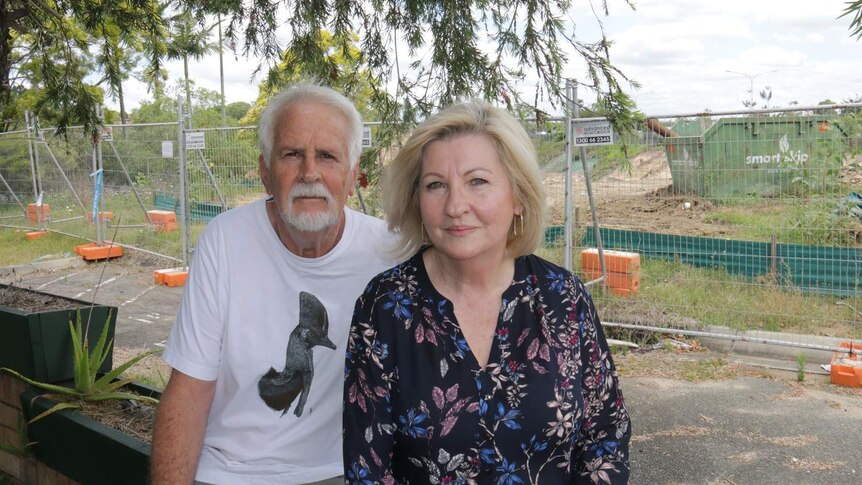 Unit owners Anthony and Julia Mayfield sit in front of construction fencing.