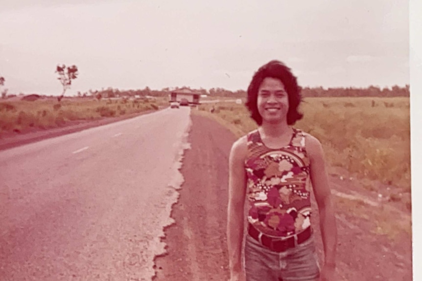 A young man stands on a road.
