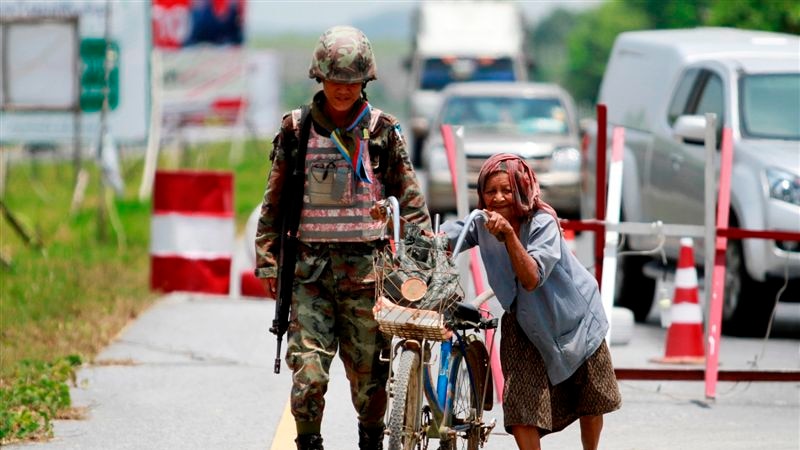 A woman pushes her bicycle through a checkpoint manned by Thai security forces in the southern province of Yala, Thailand.