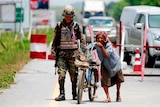 A woman pushes her bicycle through a checkpoint manned by Thai security forces in the southern province of Yala, Thailand.