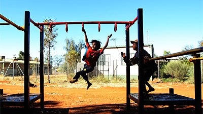 Aboriginal children play on a swingset near Alice Springs