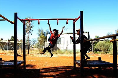 Aboriginal children play on a swingset near Alice Springs