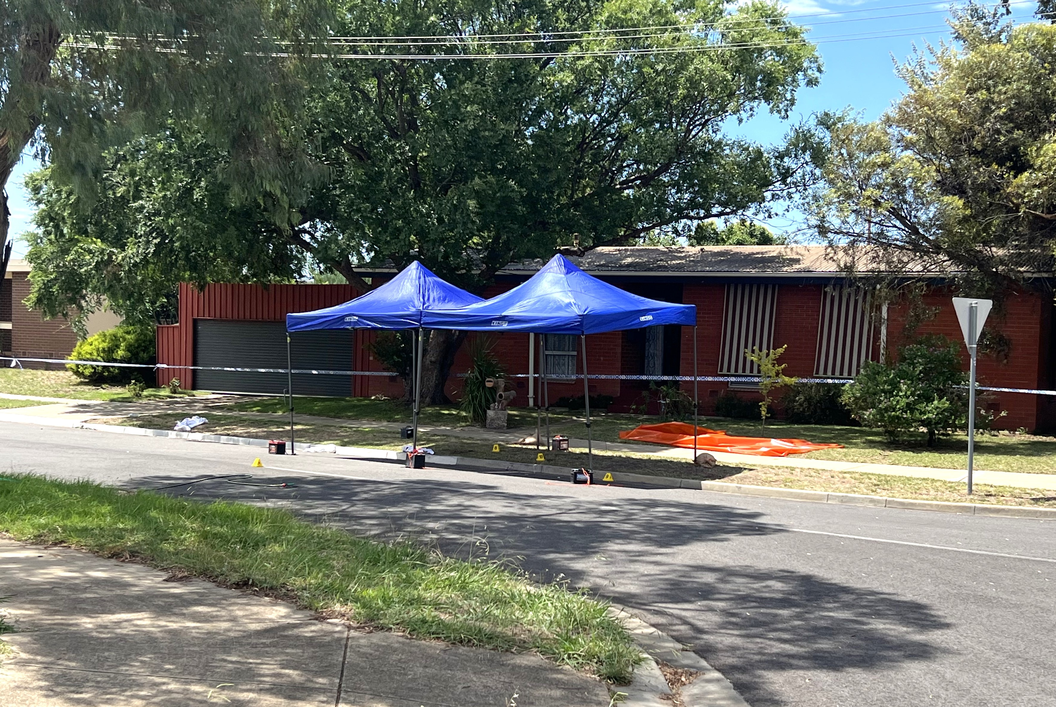 Police tape around a house with several tents also set up