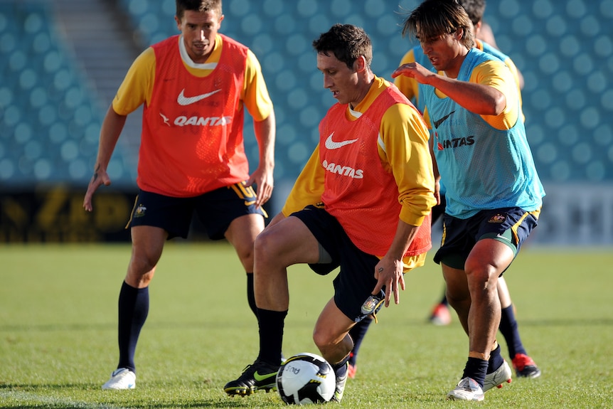 Mark Milligan dribbles the ball in training. Harry Kewell and Nick Carle are near him
