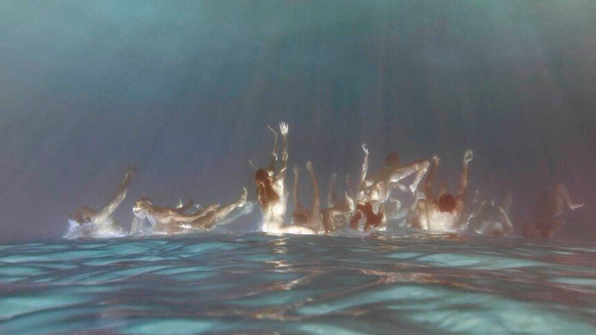 People dive into the ocean, as seen from under water, and upside down.