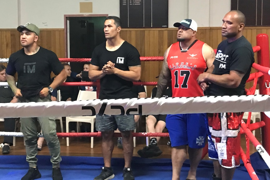 Professional athletes pose for a phot in the ring after their mentoring session to at risk youth