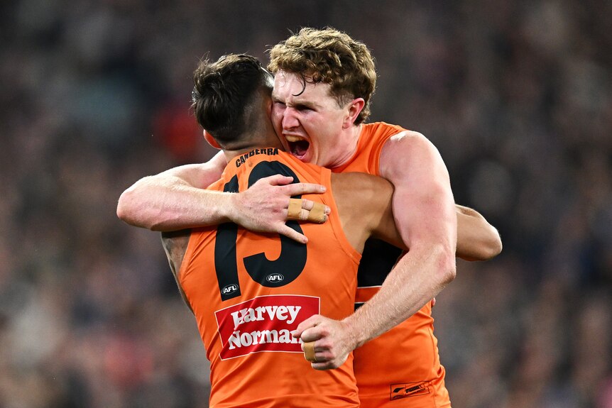 A GWS AFL player hugs a teammate as he celebrates his own goal in a final.
