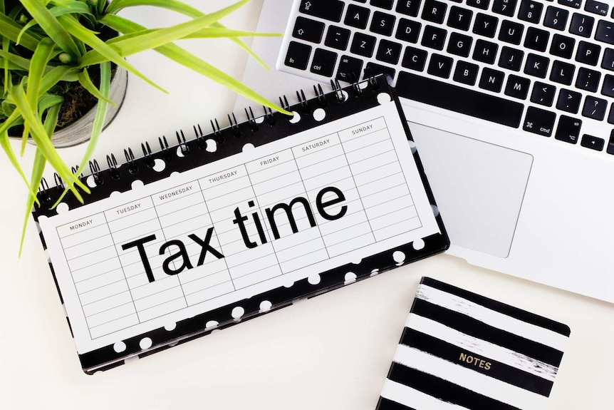 A calendar with tax time written on it beside a computer.