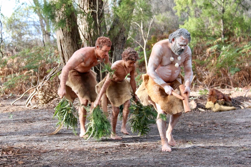 Two men and a young boy perform traditional Aboriginal dances.