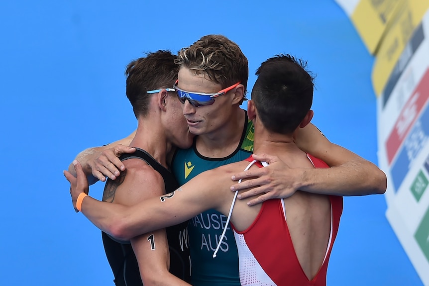 Australian Matthew Hauser hugs two other athletes after winning bronze in the Commonwealth Games triathlon.