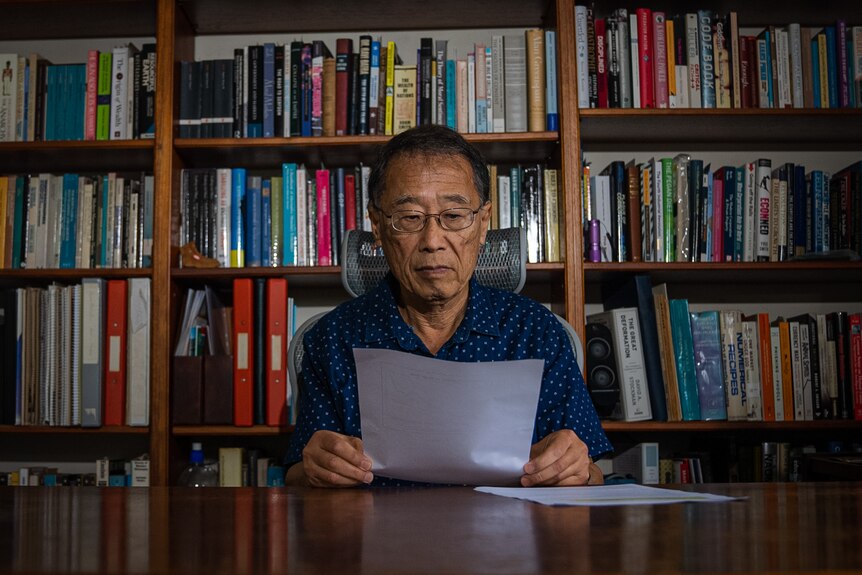 Wilson Sy reading a paper in the library of his Sydney home.