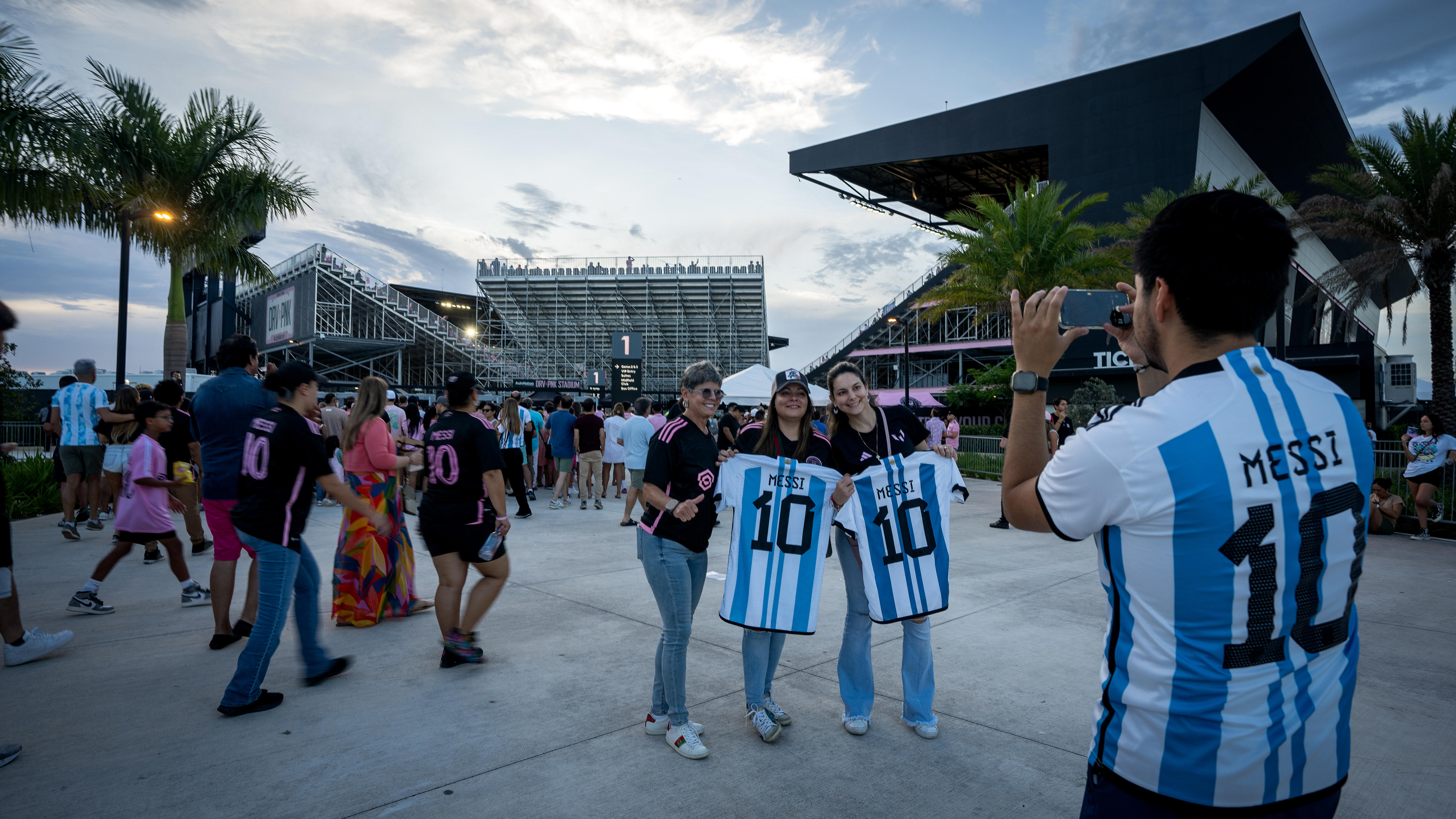 Messi fans pose with his Argentina jersey, white and blue stripes with 10 on the back, as another person takes their picture