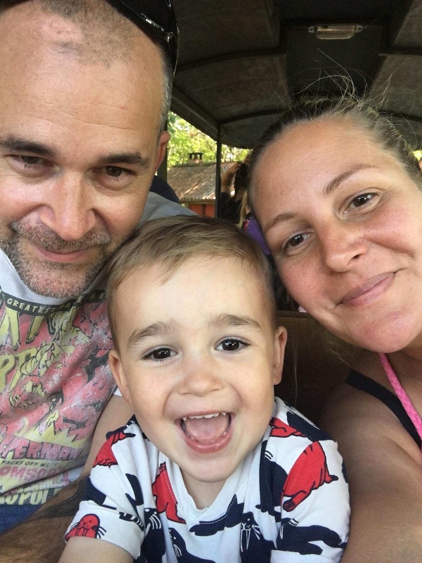 A man and woman pose with a toddler for a selfie.