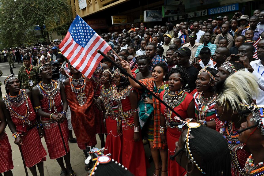 Maasai community members wave a US flag as they gather in Nairobi during the US president's visit