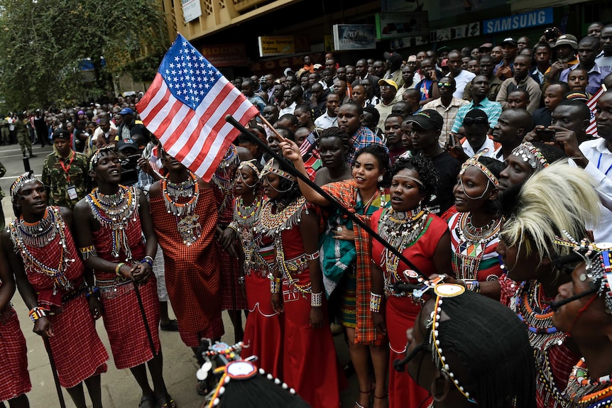 Maasai community members wave a US flag as they gather in Nairobi during the US president's visit