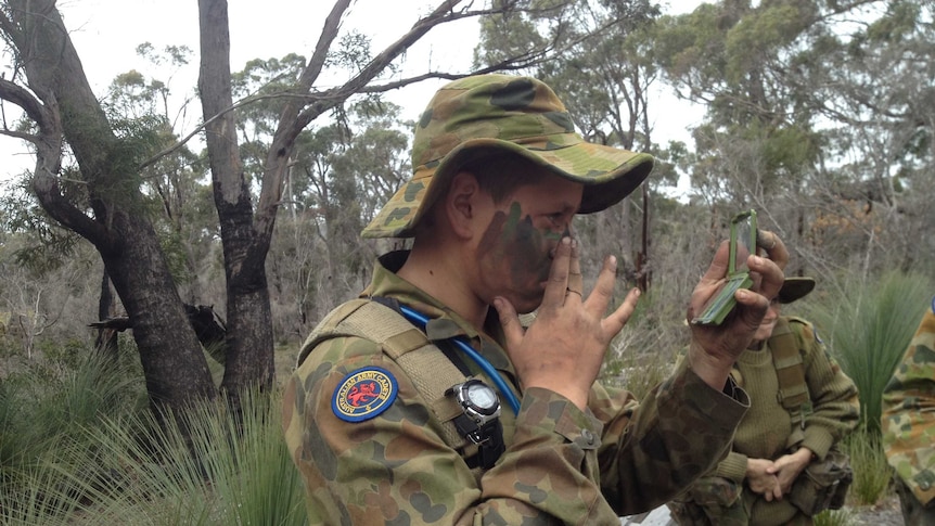 A cadet applies camouflage face paint