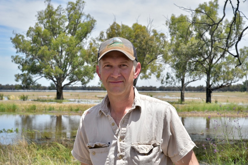 A man standing in front of a flooded paddock.