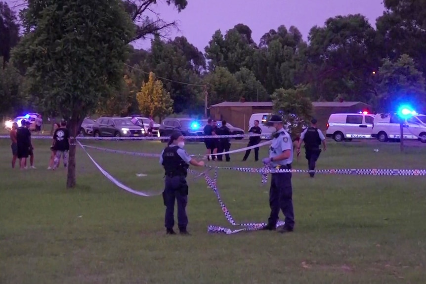 Police and bystanders with police tape outside