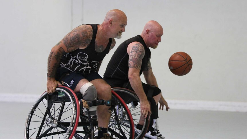 Two men in wheelchairs play basketball.