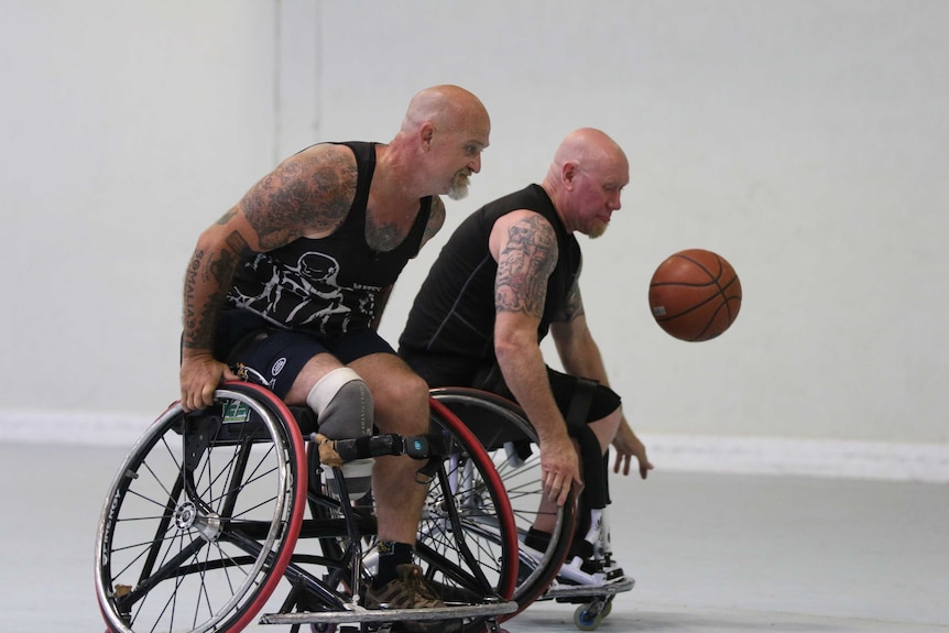 Two men in wheelchairs play basketball.