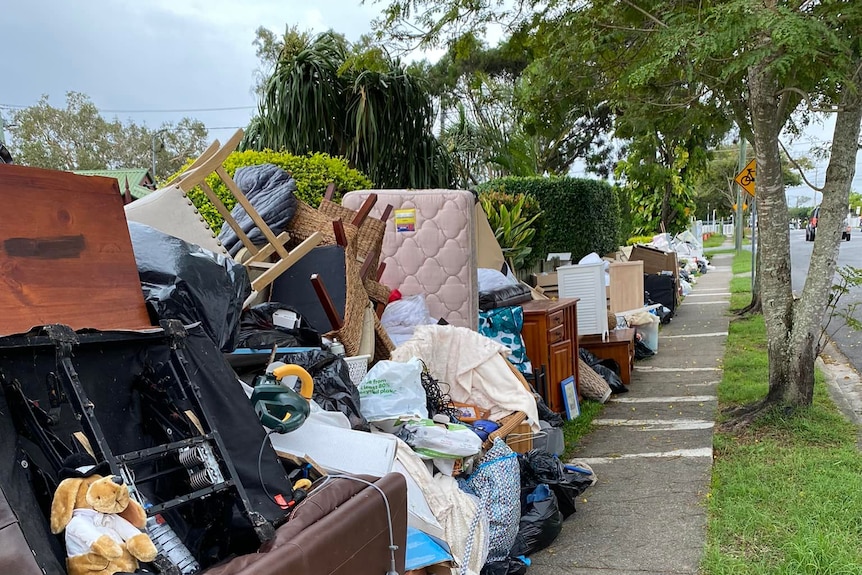 A pile of flood-destroyed goods on the side of a footpath