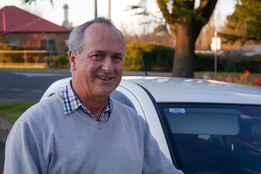 A man standing in front of a driving instructor's car