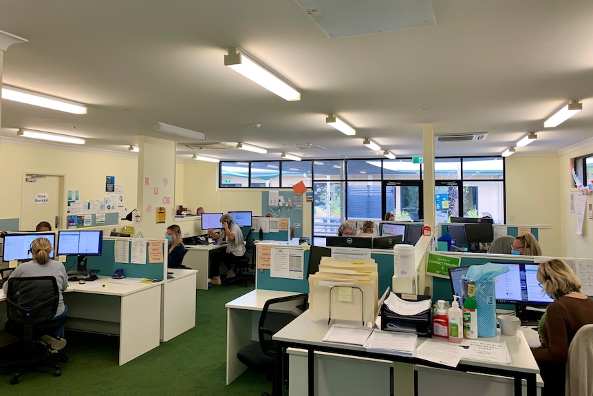 An open-plan office with people sitting at desks and on the telephone