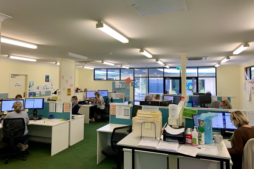 An open-plan office with people sitting at desks and on the telephone