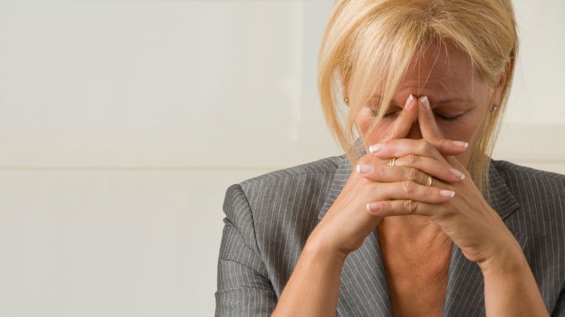 Woman with her head in her hands looking stressed.