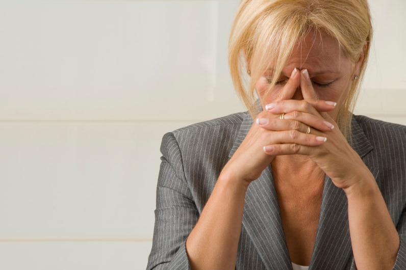 Woman with her head in her hands looking stressed.