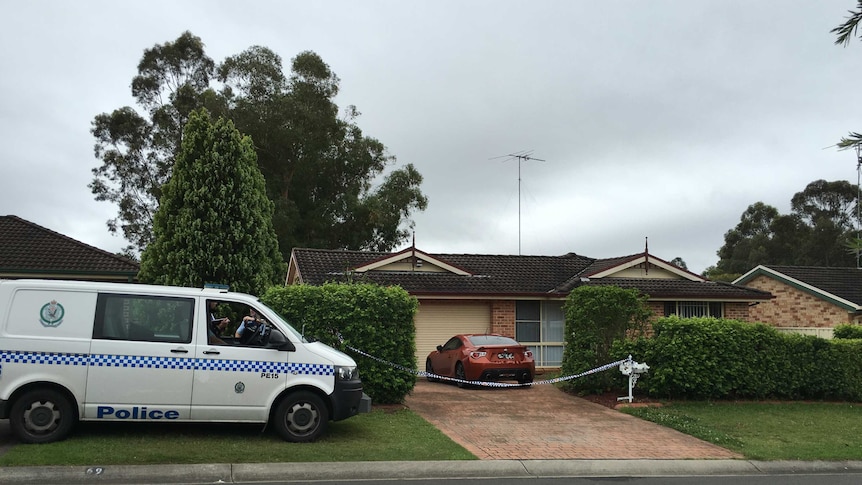 A NSW police van outside house with police tape across the driveway.