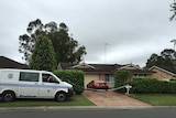 A NSW police van outside house with police tape across the driveway.