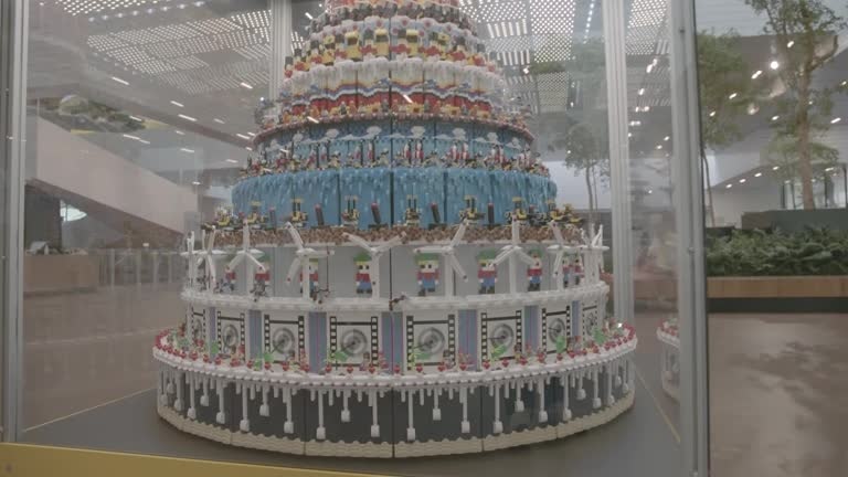 A "cake" made out of Lego and featuring nine layers sits inside a glass case. 