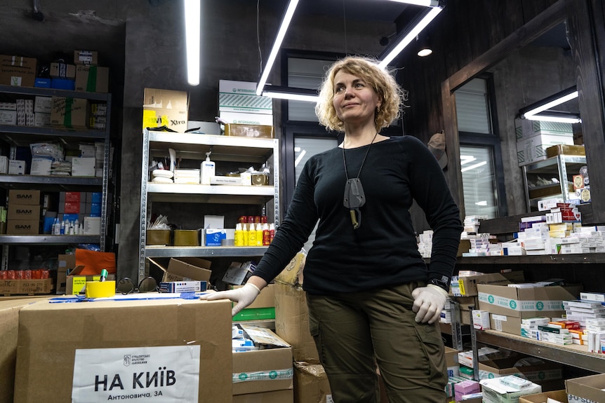 A woman with blonde hair smiles as she looks over a room with supplies.