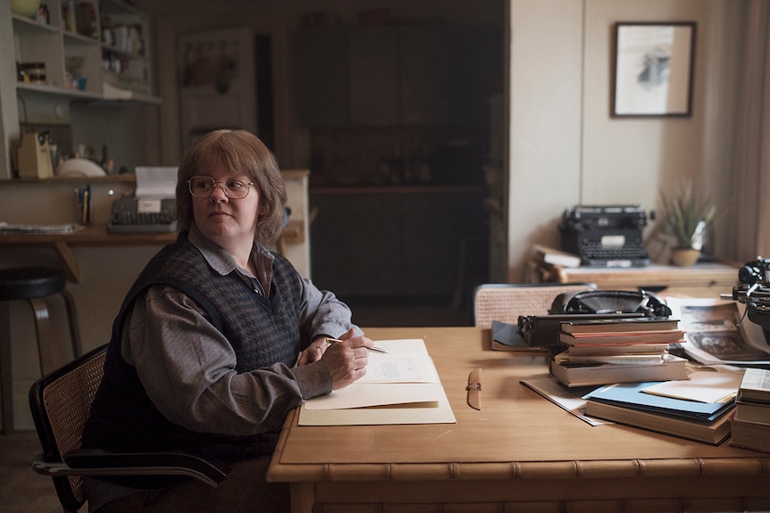 Colour still of Melissa McCarthy sitting at table writing in 2018 film Can You Ever Forgive Me?