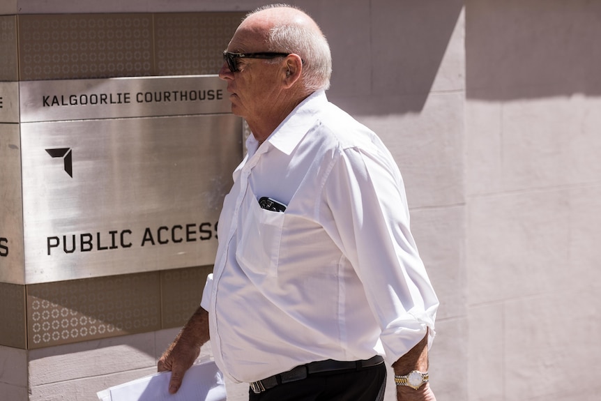 A man in a white business shirt leaves court after testifying.