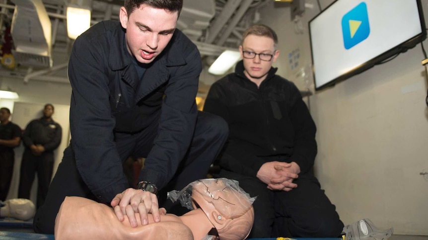 A man does chest compressions on a training dummy