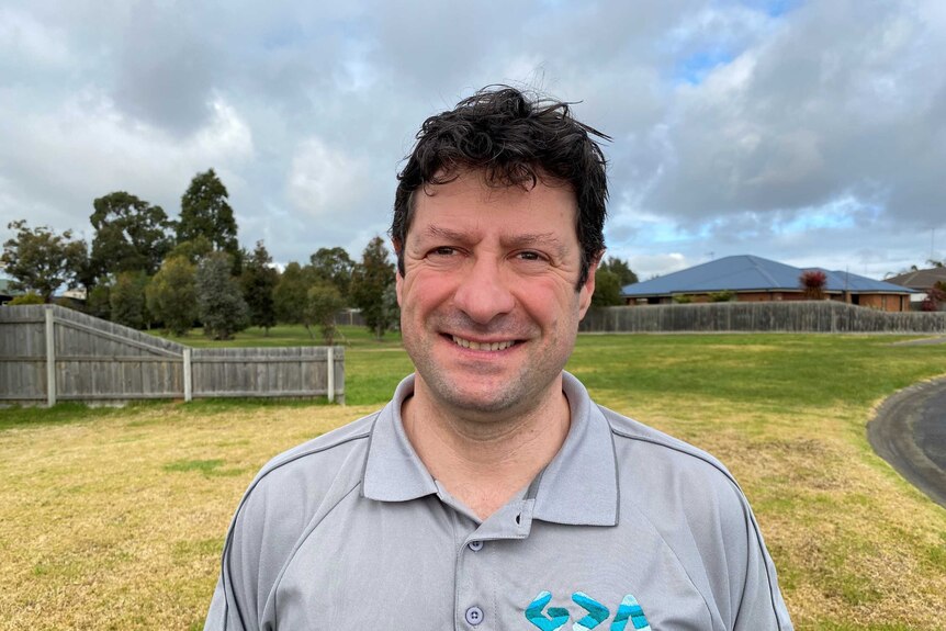 A smiling man in his 30s wearing a polo shirt.