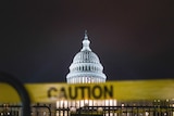 A caution sign on a fence in front of the capitol building in Washington, DC.