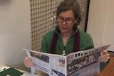 Woman across cafe table reading a newspaper