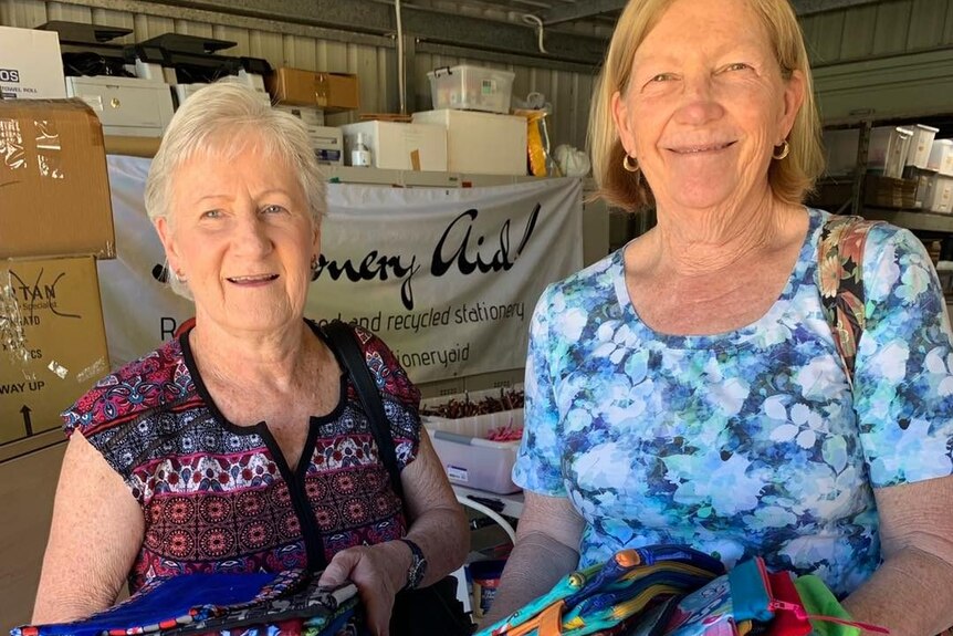 Two women holding a number of handmade pencil cases.