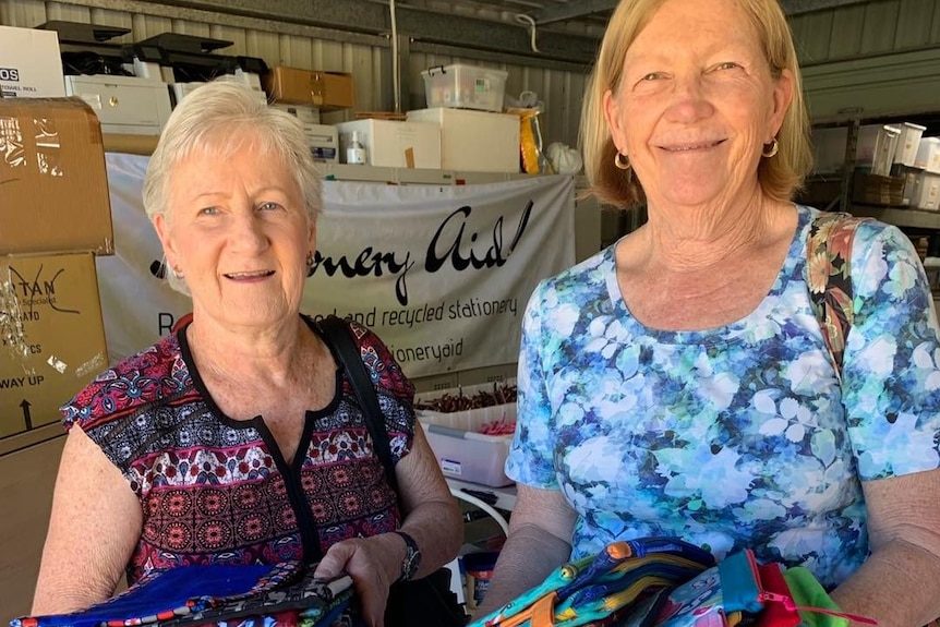 Two women holding a number of handmade pencil cases.